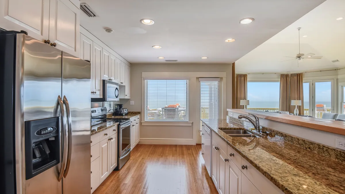 A welcoming kitchen area featuring a granite countertop, stainless steel appliances, and large windows that bathe the space in sunlight. The open design encourages socializing and makes the kitchen an extension of the living and entertaining space.
